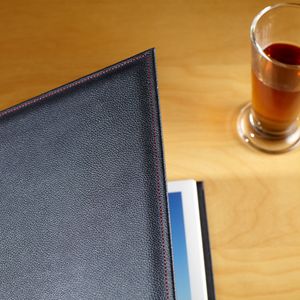 Photography portfolio lies half open on a table also with a cup of tea